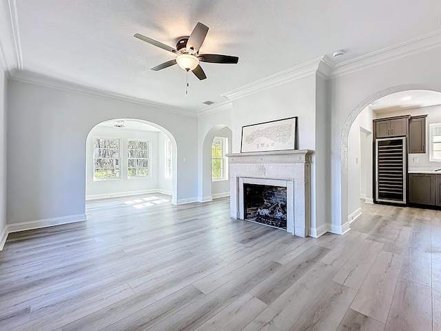 307 Minorca Ave, Saint Augustine, FL 32080 - unfurnished living room featuring beverage cooler, baseboards, a premium fireplace, crown molding, and light wood-type flooring