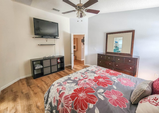 bedroom featuring a textured ceiling, light wood-type flooring, ceiling fan, and lofted ceiling