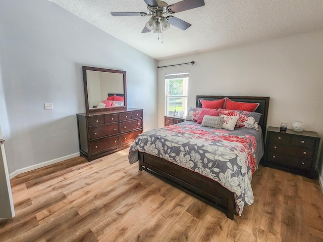 bedroom with vaulted ceiling, ceiling fan, hardwood / wood-style floors, and a textured ceiling