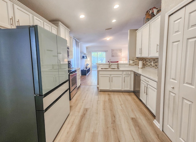 kitchen featuring kitchen peninsula, appliances with stainless steel finishes, white cabinetry, and sink