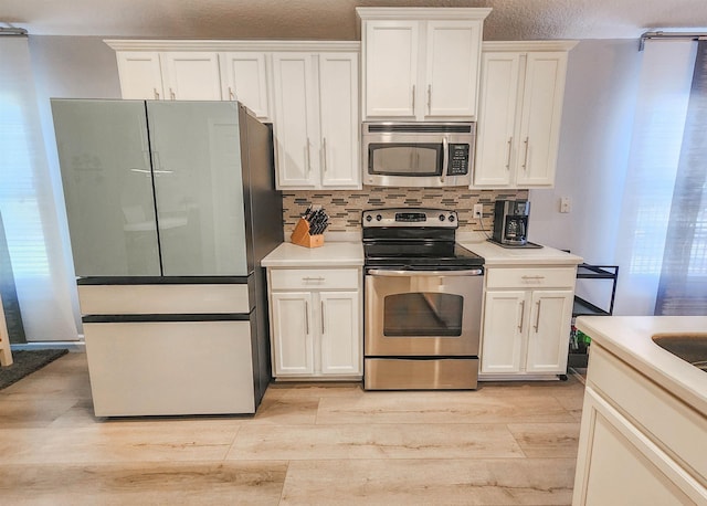 kitchen featuring tasteful backsplash, light hardwood / wood-style flooring, white cabinets, and stainless steel appliances