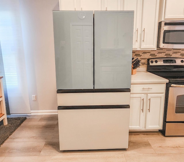 kitchen with tasteful backsplash, electric range, white cabinetry, and white refrigerator