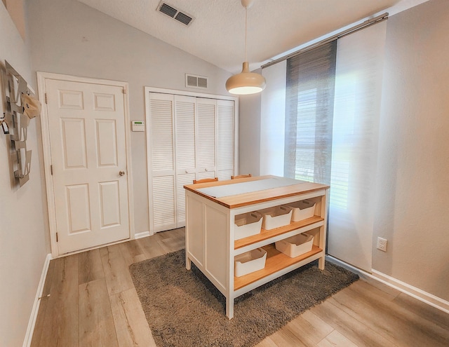 walk in closet with light hardwood / wood-style floors and lofted ceiling