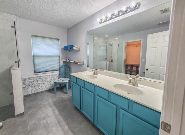 bathroom featuring tile patterned flooring, vanity, a textured ceiling, and tiled shower