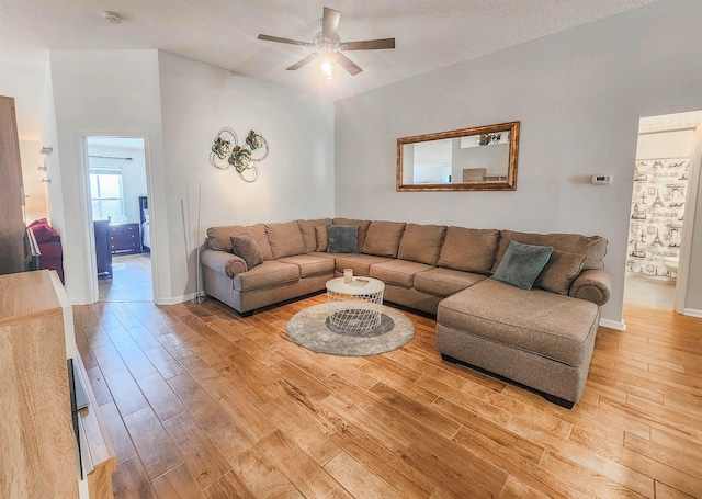 living room with ceiling fan, light hardwood / wood-style floors, and a textured ceiling