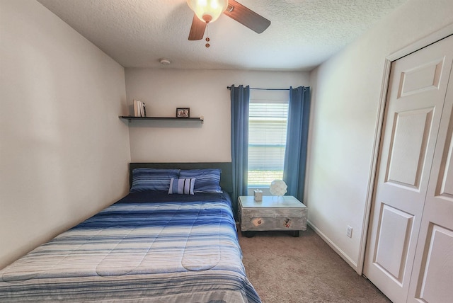 bedroom featuring carpet flooring, ceiling fan, a closet, and a textured ceiling