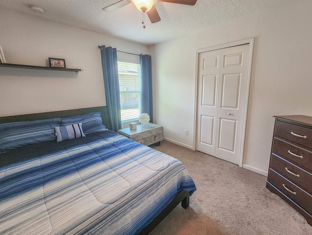 carpeted bedroom with ceiling fan, a closet, and a textured ceiling