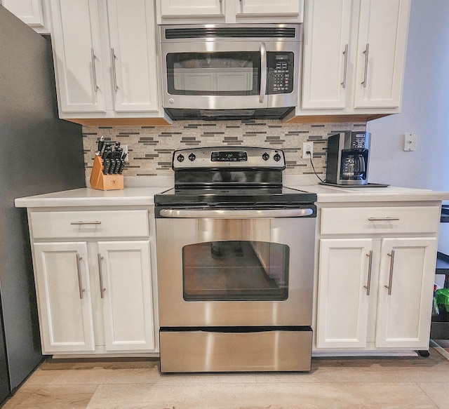 kitchen with white cabinets, decorative backsplash, and appliances with stainless steel finishes