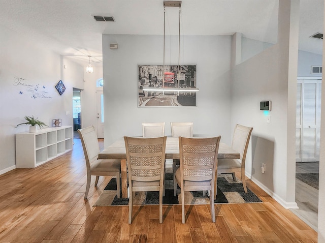 dining space featuring light hardwood / wood-style floors and vaulted ceiling