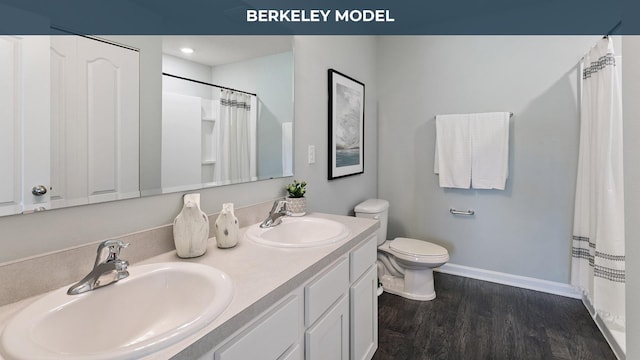 bathroom with toilet, wood finished floors, baseboards, and a sink