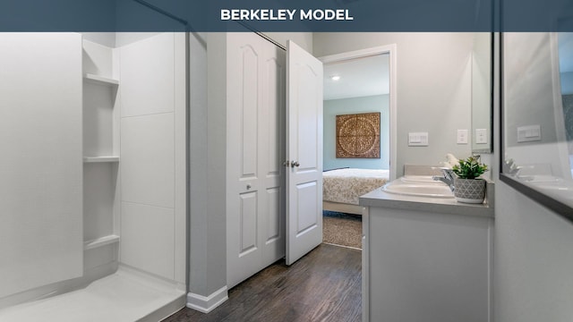 ensuite bathroom with double vanity, ensuite bath, wood finished floors, and a sink