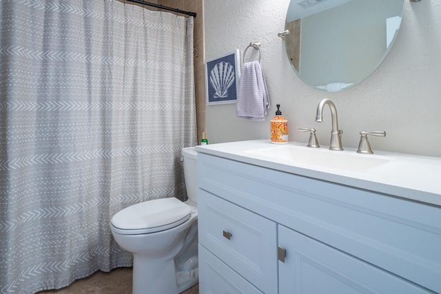 bathroom with toilet, a textured wall, and vanity
