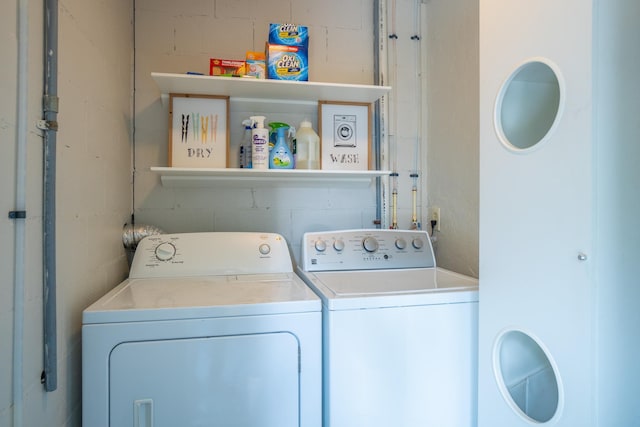 laundry area with independent washer and dryer and concrete block wall
