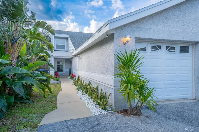 view of exterior entry with a garage and stucco siding