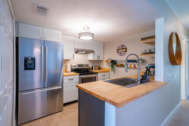 kitchen featuring appliances with stainless steel finishes, wood counters, a sink, open shelves, and under cabinet range hood