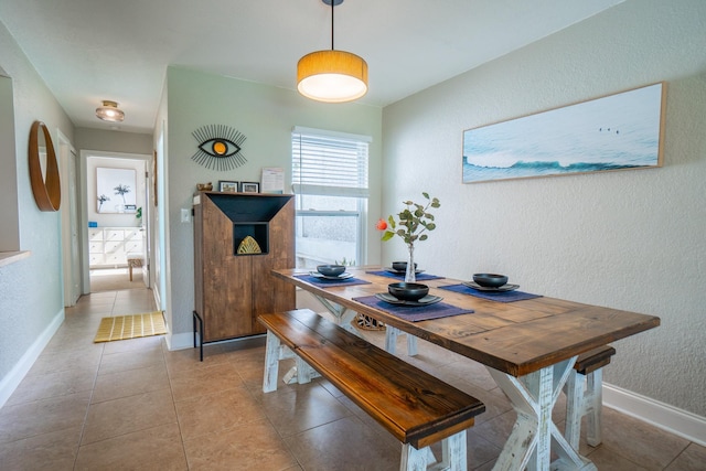 dining area with a textured wall, baseboards, and light tile patterned floors