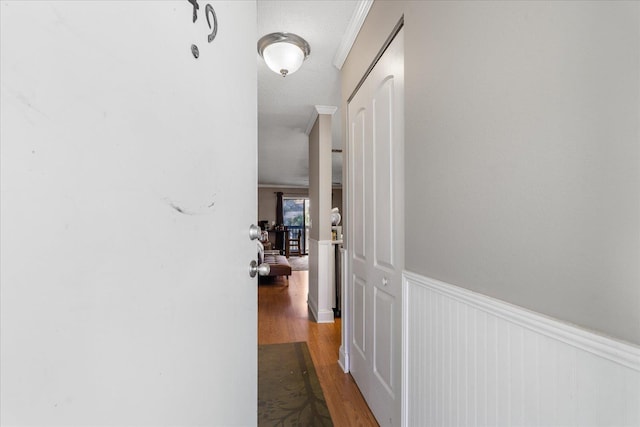 hallway featuring hardwood / wood-style floors, a textured ceiling, and ornamental molding