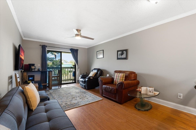 living room with a textured ceiling, hardwood / wood-style flooring, ceiling fan, and ornamental molding