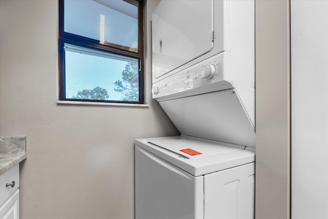 clothes washing area with cabinets and stacked washer and dryer