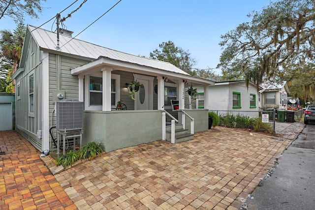 view of front facade featuring covered porch, fence, metal roof, and cooling unit