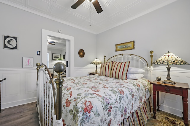 bedroom featuring a wainscoted wall, dark wood-type flooring, an ornate ceiling, and a ceiling fan