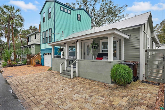 view of front of property with a garage, covered porch, metal roof, and decorative driveway