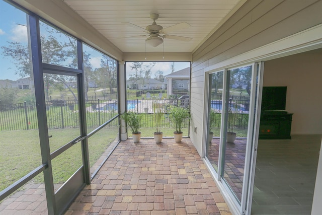 unfurnished sunroom with ceiling fan