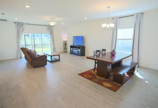 living room with ceiling fan with notable chandelier and light hardwood / wood-style floors