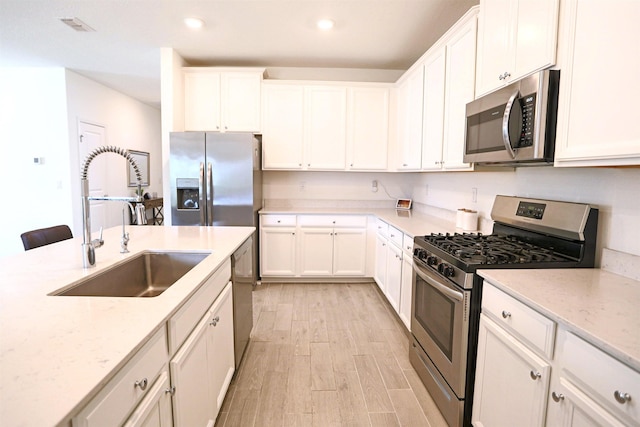 kitchen featuring white cabinets, appliances with stainless steel finishes, light wood-type flooring, and sink