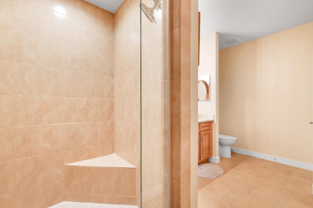 bathroom with tile patterned floors, a textured ceiling, vanity, tiled shower, and toilet