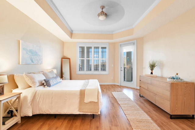 bedroom with ceiling fan, light wood-type flooring, crown molding, and a tray ceiling