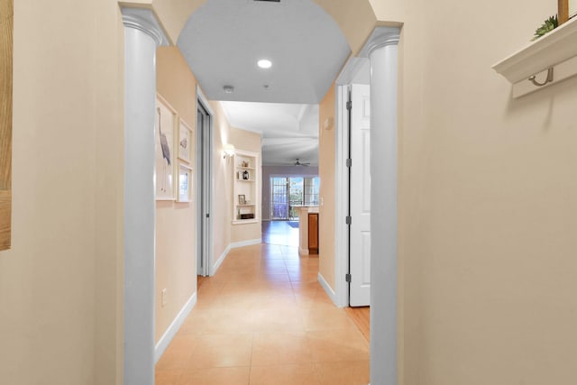 corridor featuring light tile patterned flooring and ornate columns