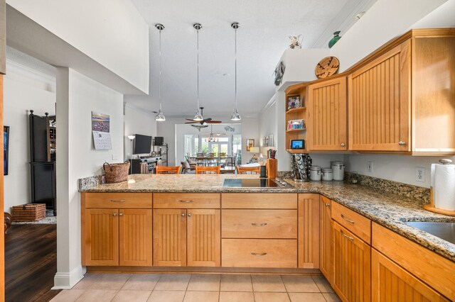 kitchen featuring ceiling fan, light stone counters, kitchen peninsula, black electric stovetop, and light tile patterned floors