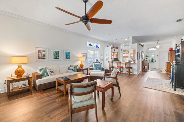 living room with dark hardwood / wood-style flooring, ceiling fan, and ornamental molding