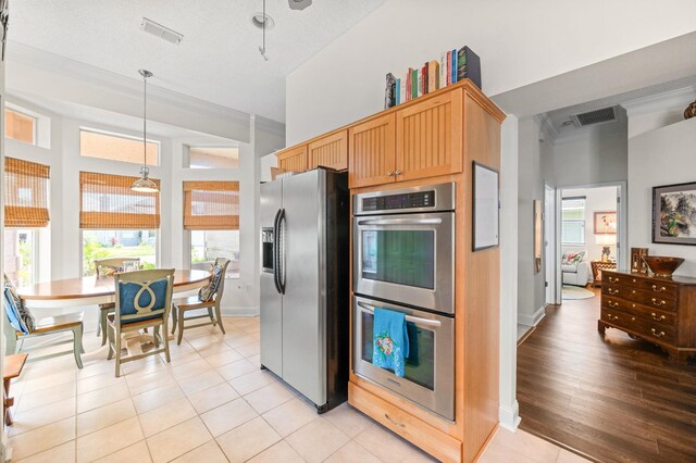 kitchen featuring hanging light fixtures, stainless steel appliances, a textured ceiling, and light hardwood / wood-style floors