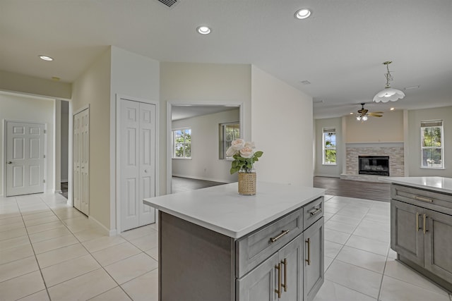 9162 August Cir, Saint Augustine, FL 32080 - kitchen featuring a ceiling fan, light tile patterned flooring, a center island, light countertops, and a glass covered fireplace