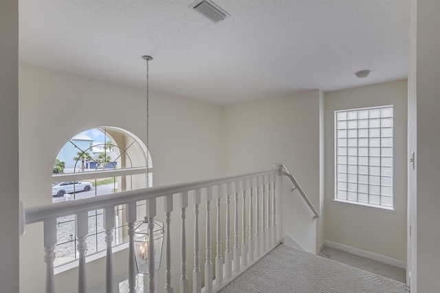 9162 August Cir, Saint Augustine, FL 32080 - hall featuring carpet flooring, an upstairs landing, a textured ceiling, and a chandelier
