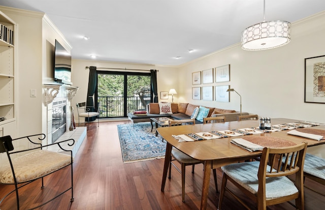 dining space featuring a glass covered fireplace, wood finished floors, and ornamental molding