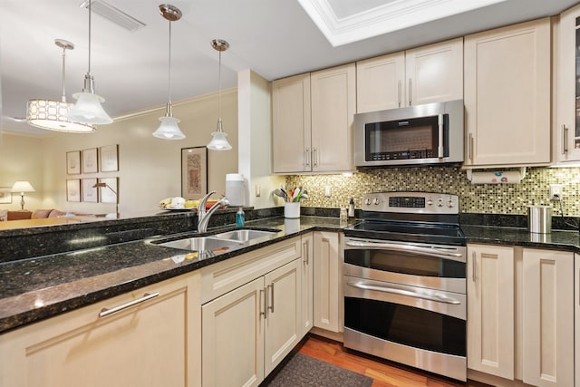 kitchen featuring backsplash, crown molding, pendant lighting, appliances with stainless steel finishes, and a sink