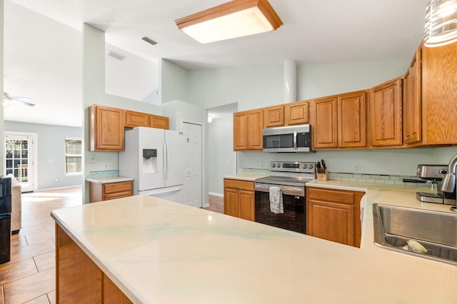 kitchen featuring light tile patterned flooring, high vaulted ceiling, stainless steel appliances, and sink