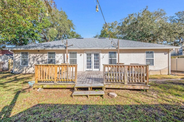 back of property with a wooden deck and a lawn