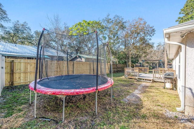 view of yard with a trampoline and a wooden deck