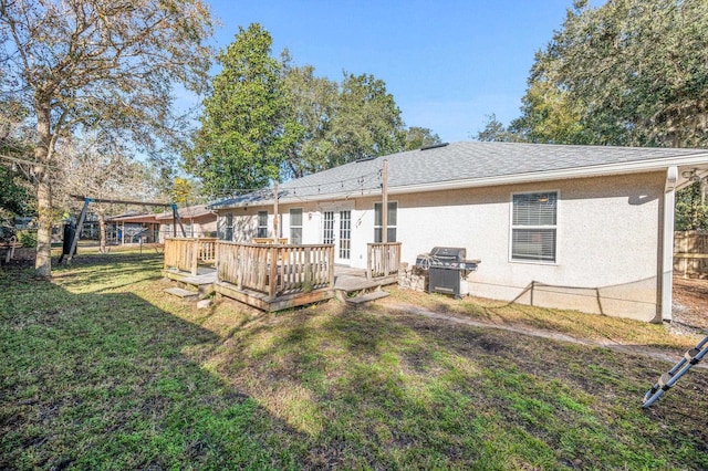 rear view of house with a wooden deck, a lawn, and french doors