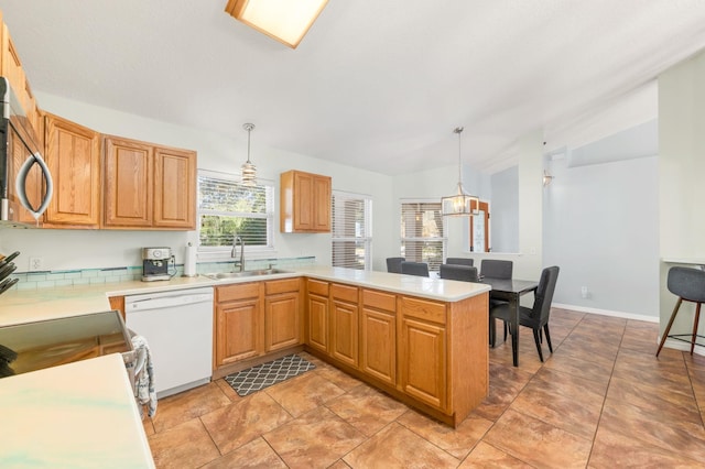 kitchen featuring lofted ceiling, sink, decorative light fixtures, white dishwasher, and kitchen peninsula