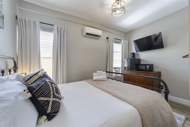 bedroom with an AC wall unit, multiple windows, and hardwood / wood-style floors