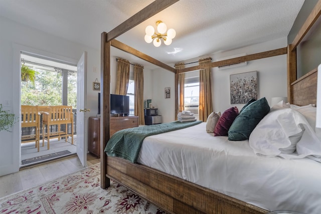 bedroom featuring a chandelier, light wood-type flooring, a textured ceiling, and multiple windows