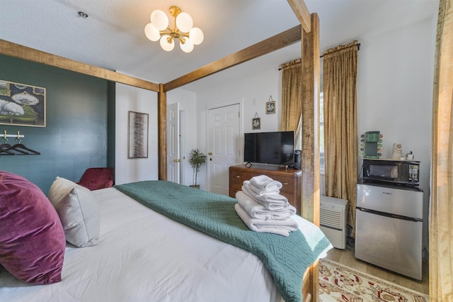 bedroom featuring a textured ceiling, stainless steel fridge, light hardwood / wood-style flooring, and a chandelier