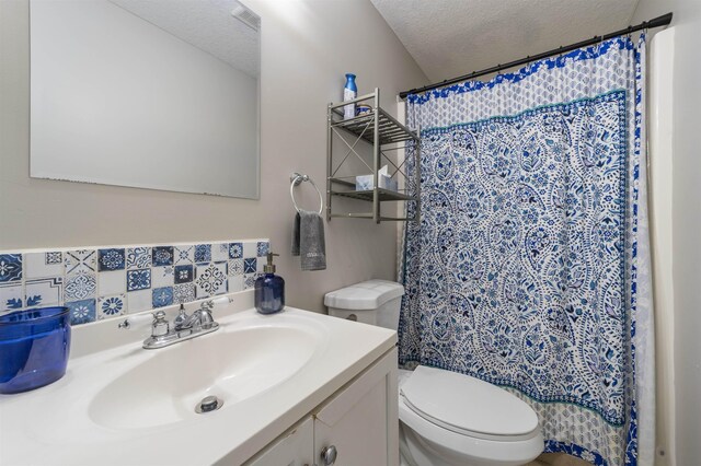 bathroom featuring a shower with shower curtain, vanity, toilet, and a textured ceiling