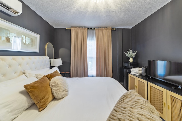 bedroom featuring an AC wall unit and a textured ceiling