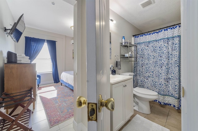 bathroom with tile patterned flooring, a textured ceiling, vanity, and toilet